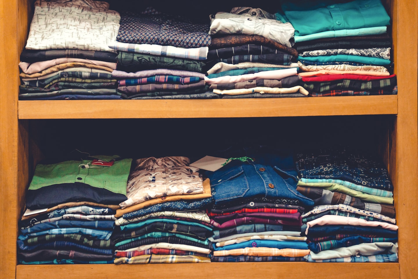 Stacks of folded clothing neatly arranged on wooden shelves.