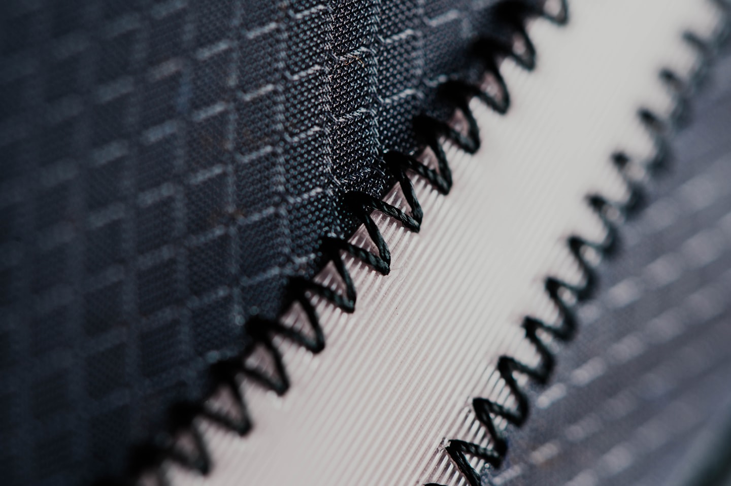 Two grey fabrics are stitched together with black thread.